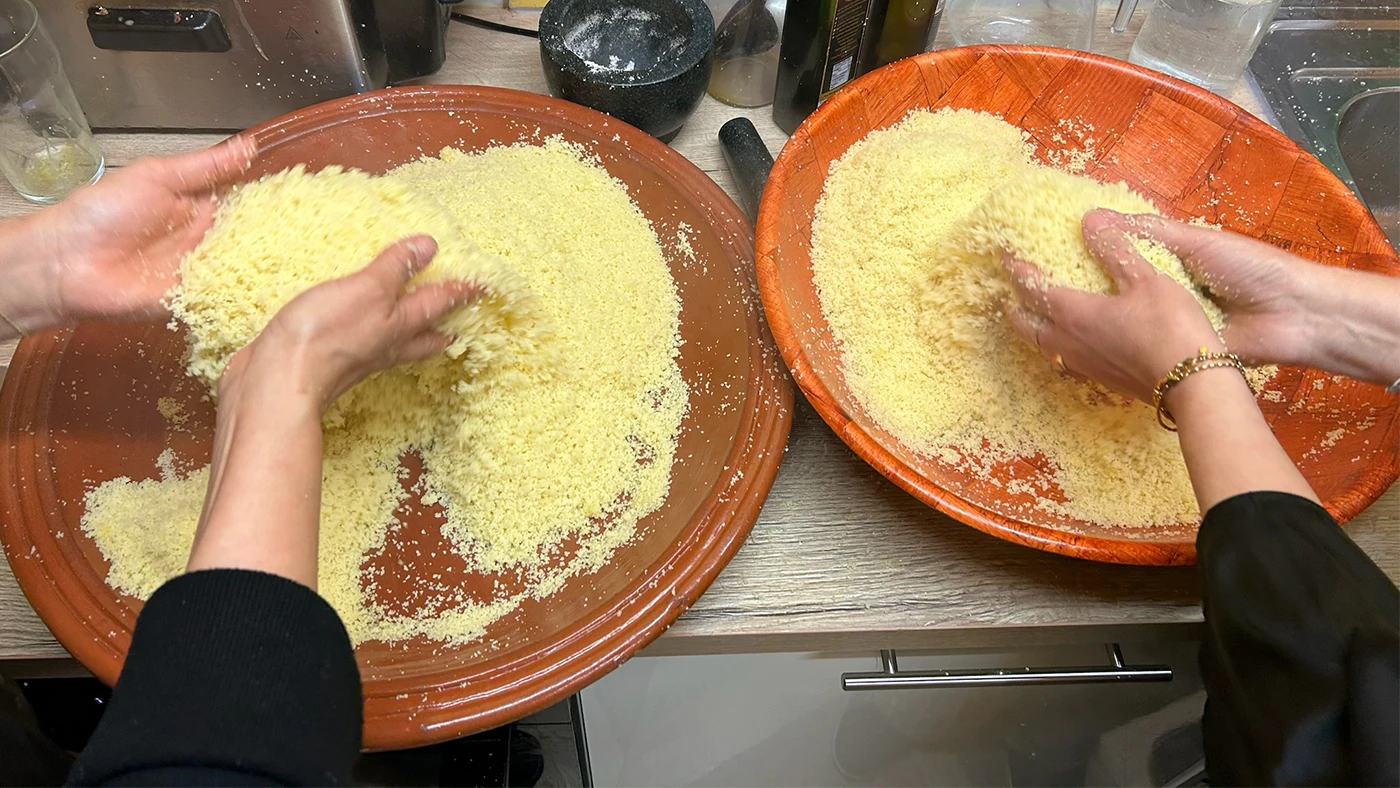 Two pairs of hands mixing couscous